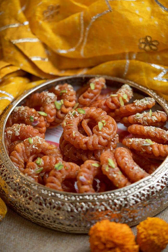 Delicious crispy jalebi served on an ornate plate with festive background.