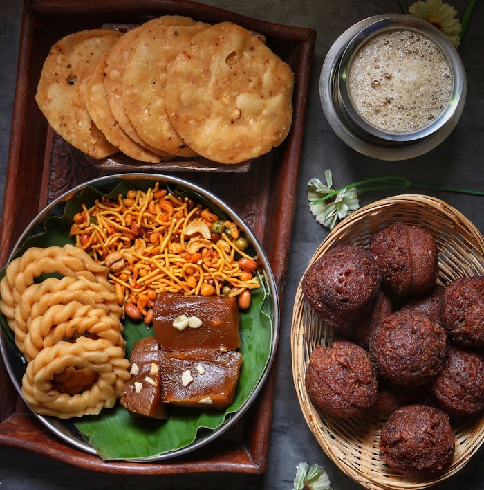 contact-img An assortment of delicious Indian snacks and sweets served in a rustic setting with tea.