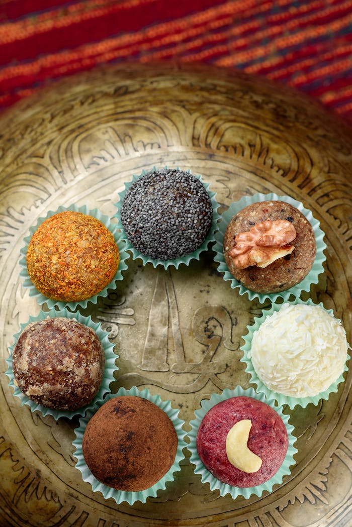 Top view of colorful Indian laddus presented on elegant brass plate, highlighting traditional flavors.