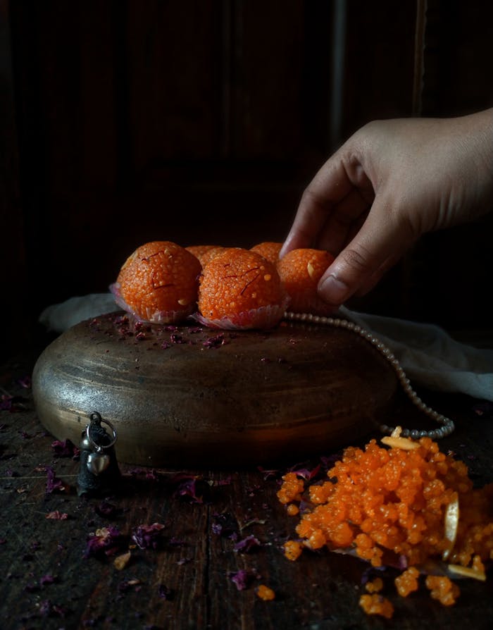 Close-up of homemade Indian laddus presented in an artistic setup with decorative elements, highlighting traditional sweets.